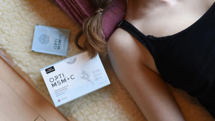En dame ligger på ryggen. I bildet synes bare hennes ene skulder og halve overkroppen, men ikke hodet. Hun har på en svart singlet og ved siden av henne ligger en boks med kosttilskuddet OptiMSM+C